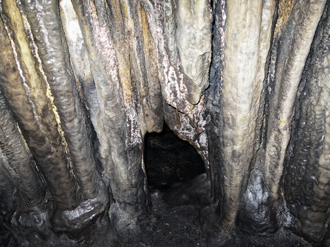 Cave interior of Baume des Lumes in France with limestone formations and narrow cat flap squeeze opening