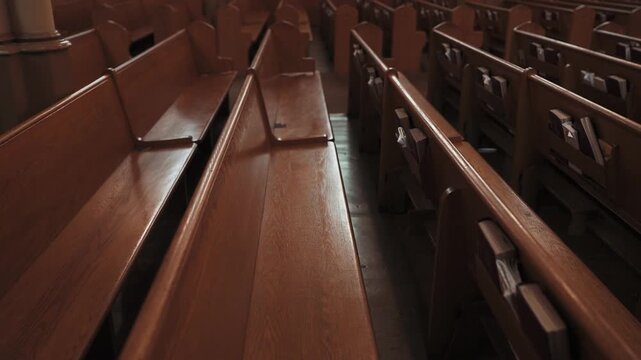 Rows of Empty Wooden Church Pews with Hymnals in a Dimly Lit Sanctuary