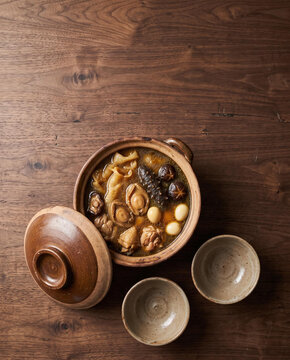 Buddha Jumps Over the Wall soup in a clay pot with abalone, sea cucumber and fish maw for Chinese New Year, top view with copy space, vertical