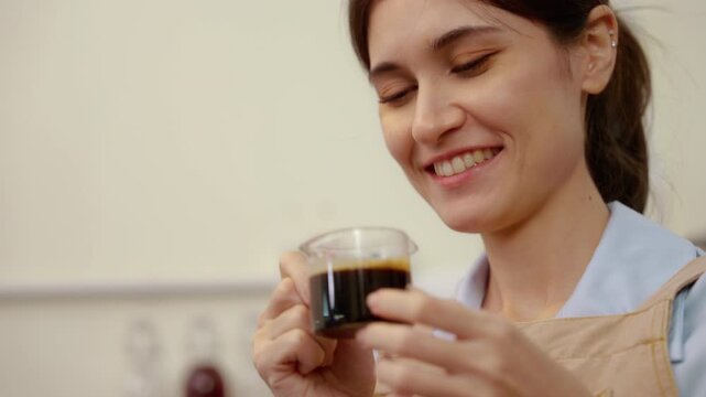 Close-up of a female barista appreciating the aroma of freshly brewed espresso, highlighting coffee tasting, sensory evaluation, specialty coffee craftsmanship, and beverage quality.

