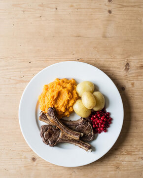 Norwegian Christmas pinnekjott lamb ribs with mashed rutabaga, potatoes and lingonberries, top view with copy space, vertical