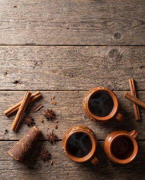 Mexican cafe de olla in clay jarritos with cinnamon, piloncillo and star anise, top view with copy space, vertical