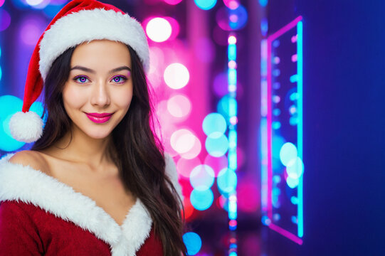 young adult woman with long dark wavy hair in red santa hat and red off-shoulder santa costume with white fur trim smiling slightly before neon pink blue and purple bokeh lights