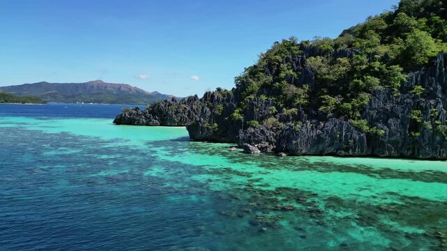 Aerial view of jagged limestone cliffs rising from turquoise waters and coral reefs at Coron Island in Coron, Mimaropa, Philippines.