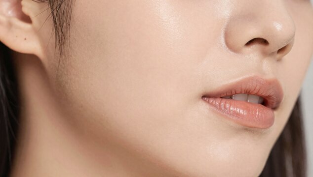 Close-up macro shot of a young woman's healthy, glowing skin and full lips with a hint of gloss