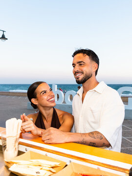 Happy young couple enjoying evening on beach promenade