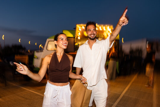 Smiling couple pointing enjoying festival atmosphere at night