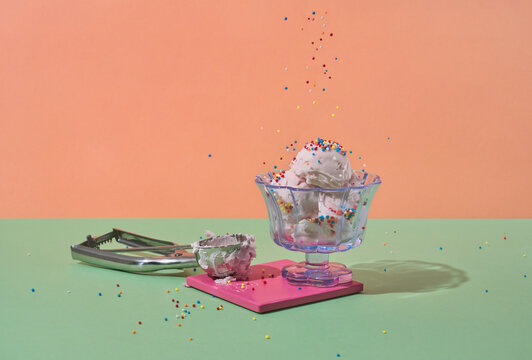 Sprinkles fall onto pink ice cream scoop