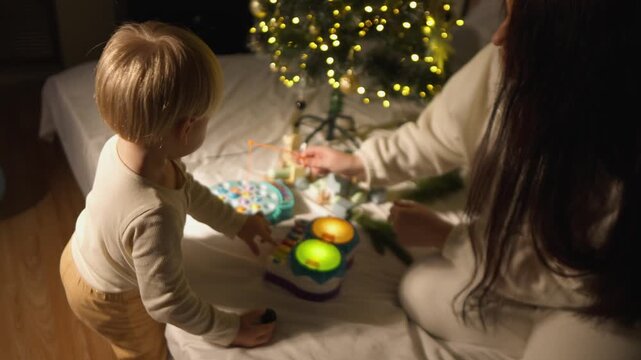 Warm holiday footage features a young boy who shares a playful holiday moment with his mother on a cozy bed. This candid family scene illustrates family connection, winter joy and togetherness.