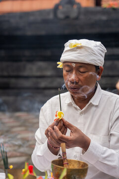 Man Offers a Prayer With Incense in a Temple Setting