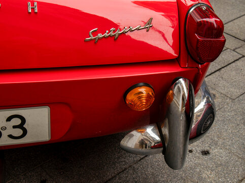 GANDIA, SPAIN - OCTOBER 4, 2026: Rear view detail of a classic red Triumph Spitfire 4 sports car, showing the chrome bumper overrider, tail light, and vintage script emblem.