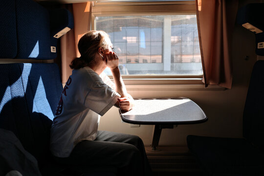 Woman looking out train window while drinking coffee in compartment