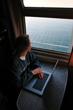 Woman working on laptop in train compartment by ocean view