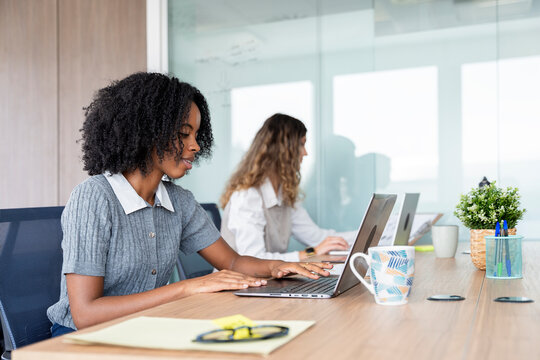 Diverse businesswomen working on laptops in modern office