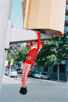 a mischievous Christmas elf hangs from a traffic light, 35mm film