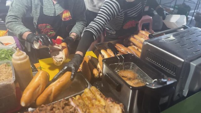 A colourful display of grilled meats, skewers, sausages, and roasted pieces ready for serving at a Vietnamese takeaway food counter in a busy night market.