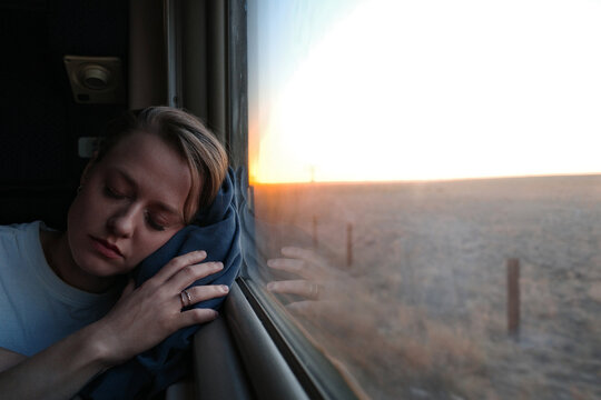 Woman resting on train journey at sunset