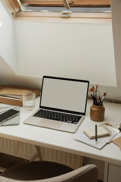 Laptop computer mockup on desk below open roof skylight window