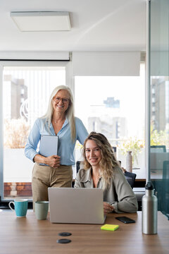 Businesswomen collaborating in modern office working on laptop