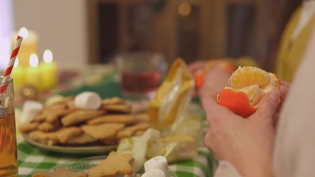 Detailed holiday footage captures hands as they hold a bright citrus fruit above cookies and holiday decorations. Close hand view presents seasonal food preparation with strong commercial appeal.