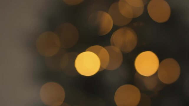 Golden blurred bokeh circles glow softly against a dark background, evoking warmth and celebration. This abstract image is ideal for seasonal, festive, or elegant visual content