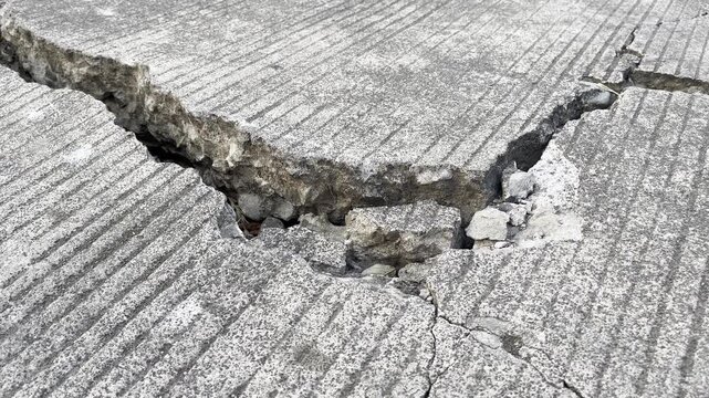 Severely cracked and damaged concrete road surface close up