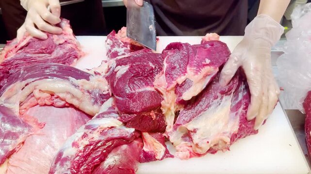 Butcher Hands Cutting Beef into Pieces and Thin Slices &ndash; Meat Shop Preparation
