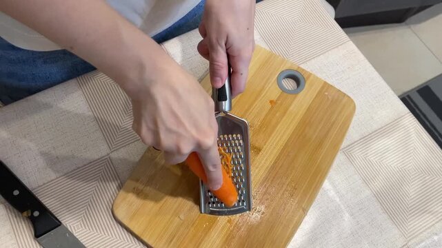 Carrot shred session, Orange vegetable being grated smoothly, Fine orange carrot shreds collected for salad preparation, Bright orange carrots are shredded gently on wooden board for fresh salad