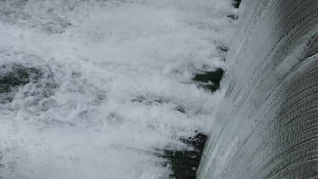Close up of roaring water flowing over a dam weir