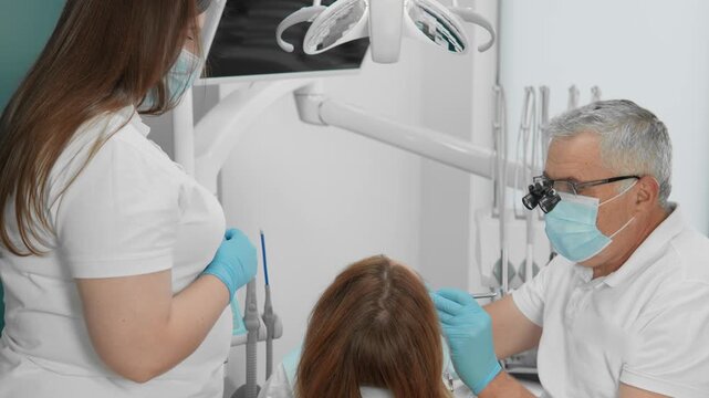 Experienced dental professionals provide oral care to a patient in a contemporary dental office. The team uses advanced equipment and follows strict health protocols for optimal results