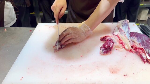 Chef Hands in Gloves Thinly Slicing Premium Beef on White Professional Surface &ndash; Preparing Thin Translucent Meat Layers for Gourmet Dish