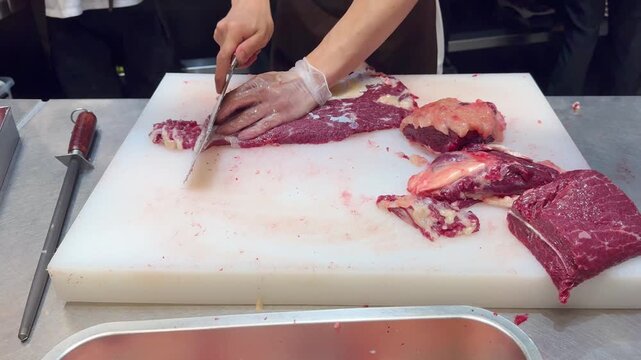 Chef Hands in Gloves Thinly Slicing Premium Beef on White Professional Surface &ndash; Preparing Thin Translucent Meat Layers for Gourmet Dish