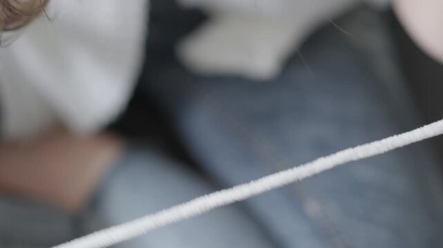 A person&rsquo;s hands are carefully tying a white shoelace, with attention to detail and precision. The soft focus on denim jeans in the background enhances the casual, everyday atmosphere