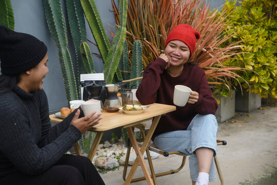 Coffee drip camping friend woman, sitting and talking near cactus garden background, during outdoor winter leisure activity in cozy home backyard for lifestyle concept