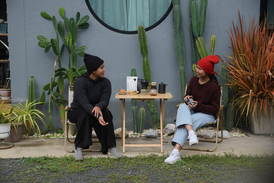Coffee drip camping friend woman, sitting and talking near cactus garden background, during outdoor winter leisure activity in cozy home backyard for lifestyle concept