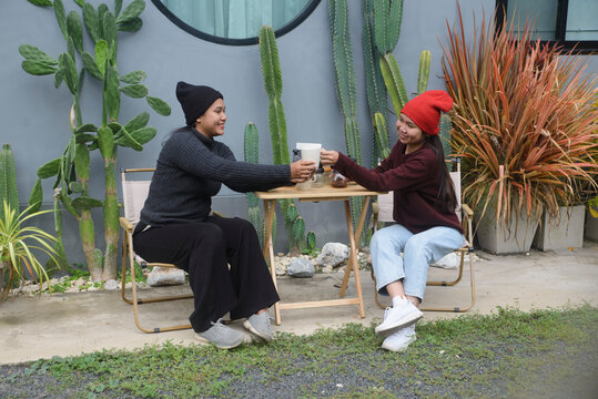 Coffee drip camping friend woman, sitting and talking near cactus garden background, during outdoor winter leisure activity in cozy home backyard for lifestyle concept