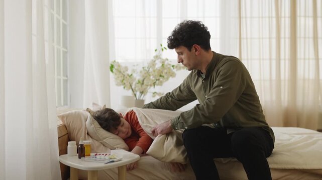 Compassionate dad cares for ill son sleeping in bed with visible flu symptoms