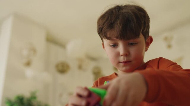 Focused little boy enjoys building with colorful magnetic toy blocks at home