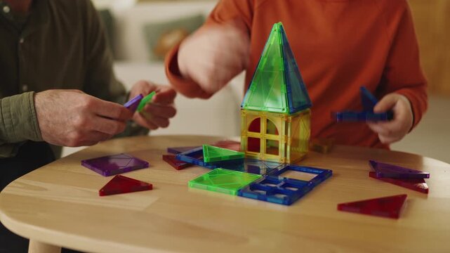 Little boy and his father assemble colorful magnetic toy blocks together