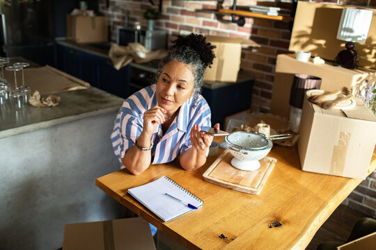 Woman recording voice memo while unpacking in kitchen