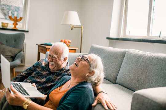 Senior couple laughing with laptop on living room floor
