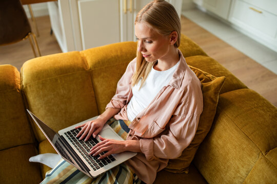 Woman typing on laptop on sofa at home