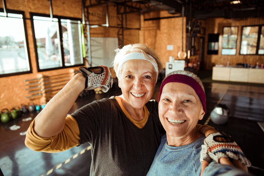 Two senior women take a gym selfie with a flexed arm