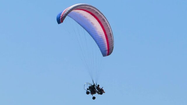 Motorized paramotor trike with paragliding wing soaring straight through empty azure air space