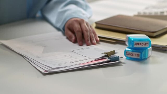 Business Professional Man Reviewing Documents and Files at Desk with Office Supplies and Folders in Modern Workspace