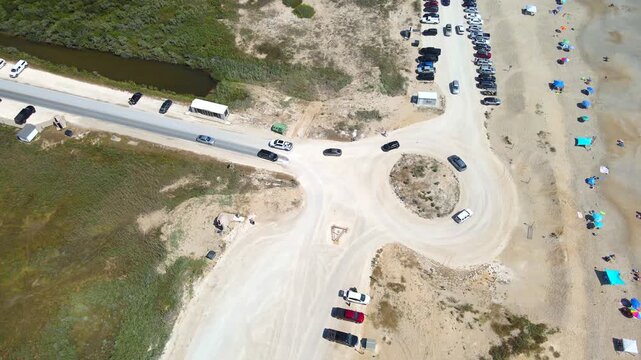 Rows of cars separate beach umbrellas from marshland near the Chincoteague shore.