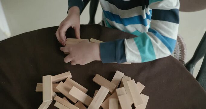 Close-up children's hands play with wooden bricks constructing structures. 4K 10-bit