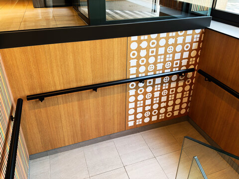 Modern wooden staircase with black railings and geometric wall pattern in a bright retail interior in Barcelona, Spain