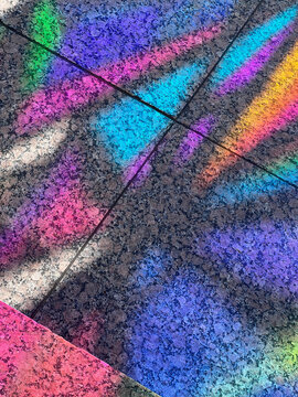 Rainbow prism light falling on speckled granite paving