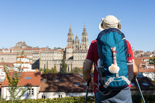 A pilgrim with a backpack and a scallop shell, gazing at the Cathedral of Santiago de Compostela in the distance in the city